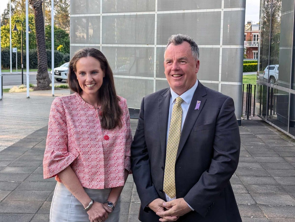 a smiling woman and man in front of a city council building 