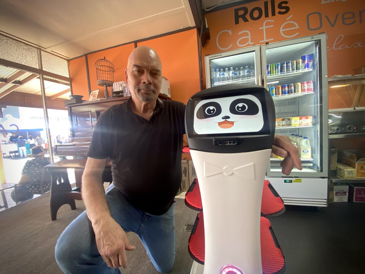 man with a robot in his cafe