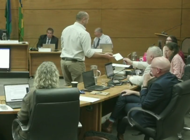 man voting at a city council meeting