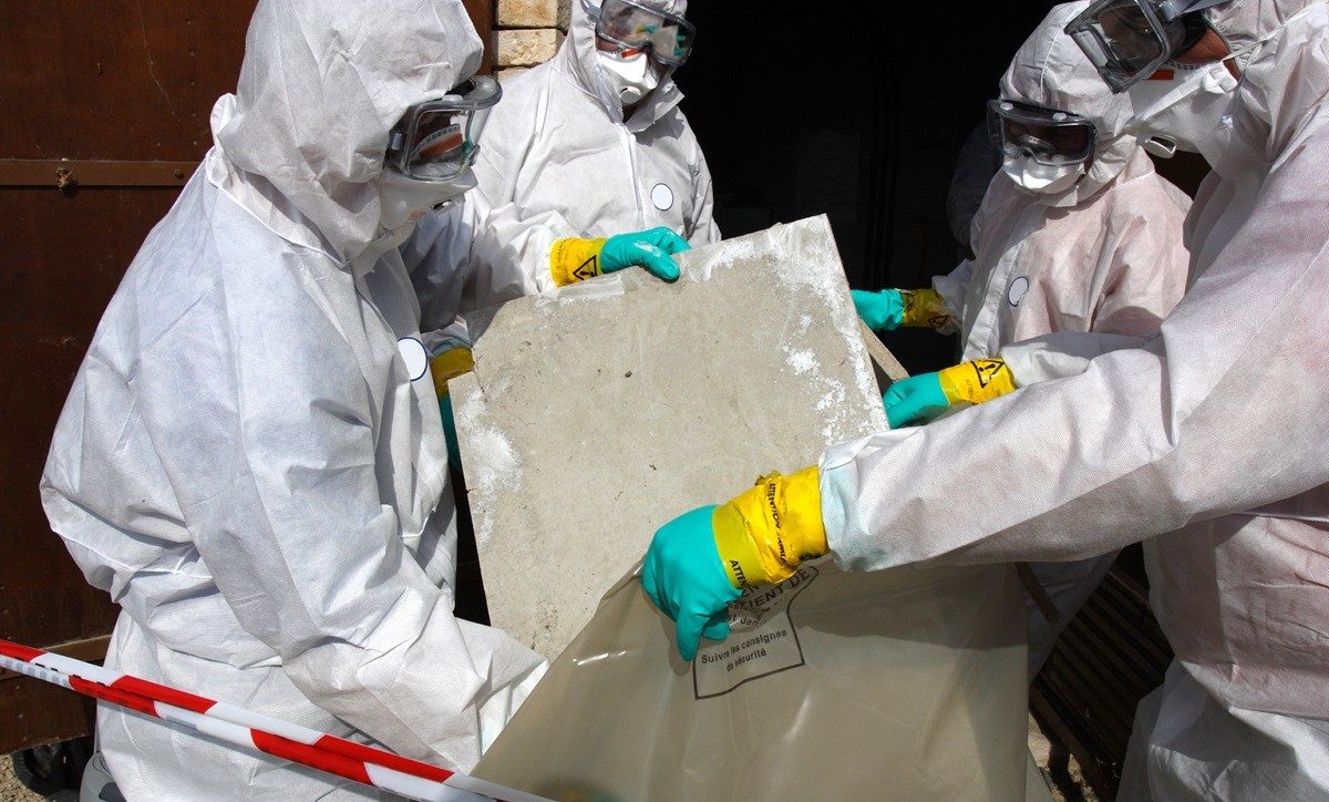 a group of people removing asbestos sheets