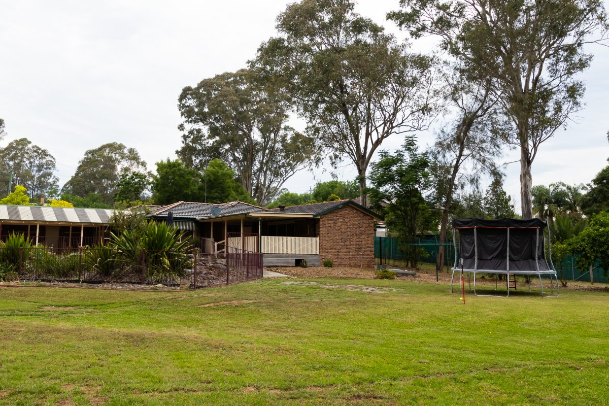 house with trees in background and grassed area in front