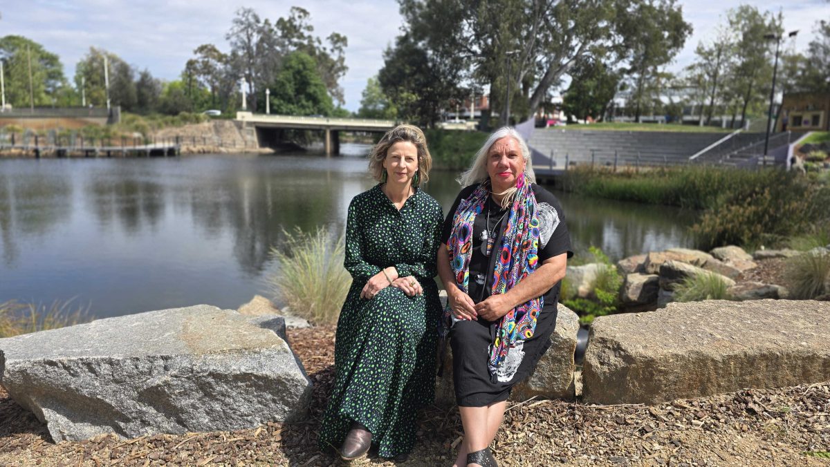 two women sitting by a lagoon