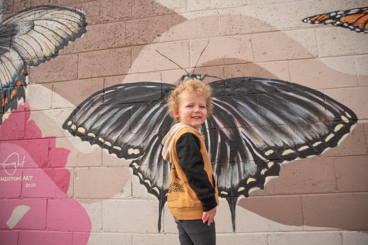 boy in front of butterfly mural 