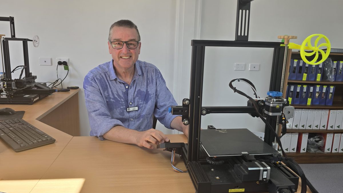 a smiling man sitting at a desk in an office