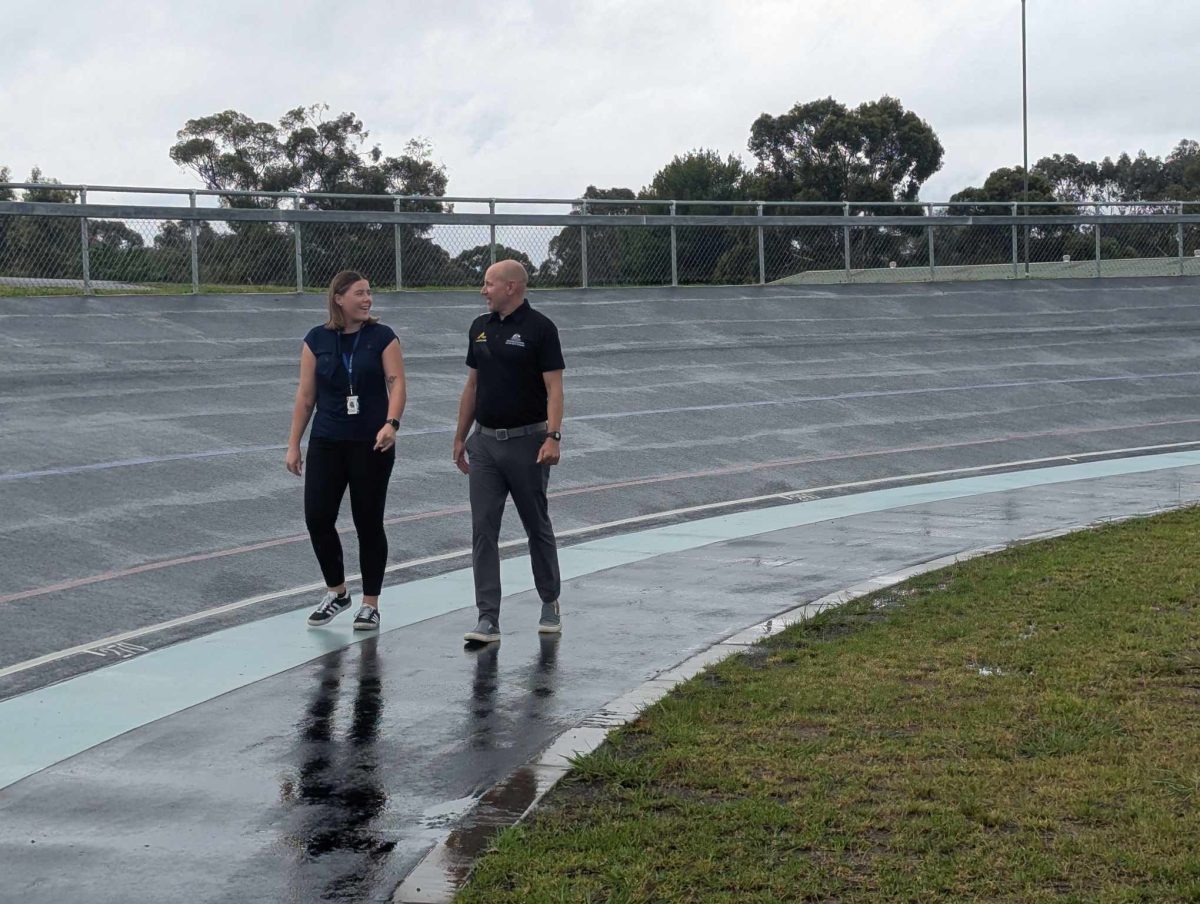 A woman and a man walking along an outdoor velodrome