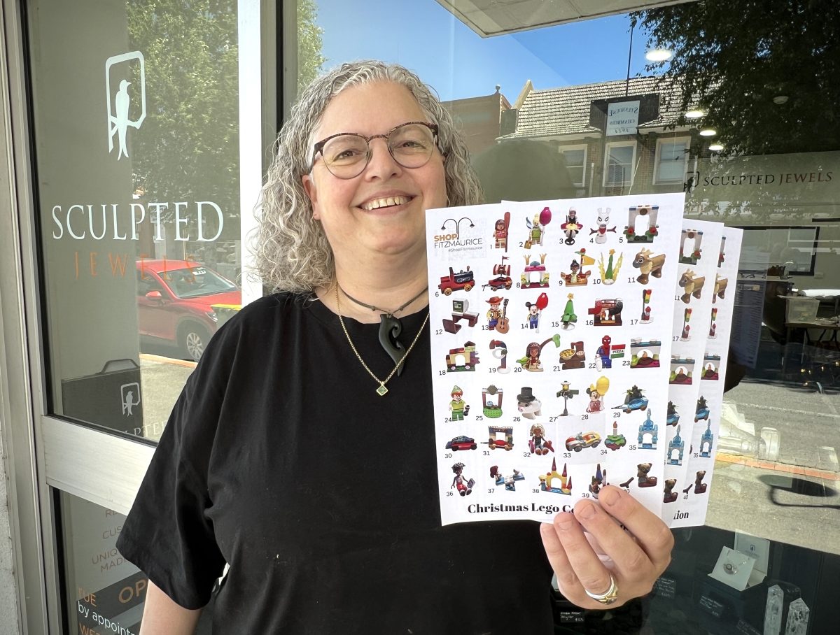 A woman holding a sheet of stickers outside her shop