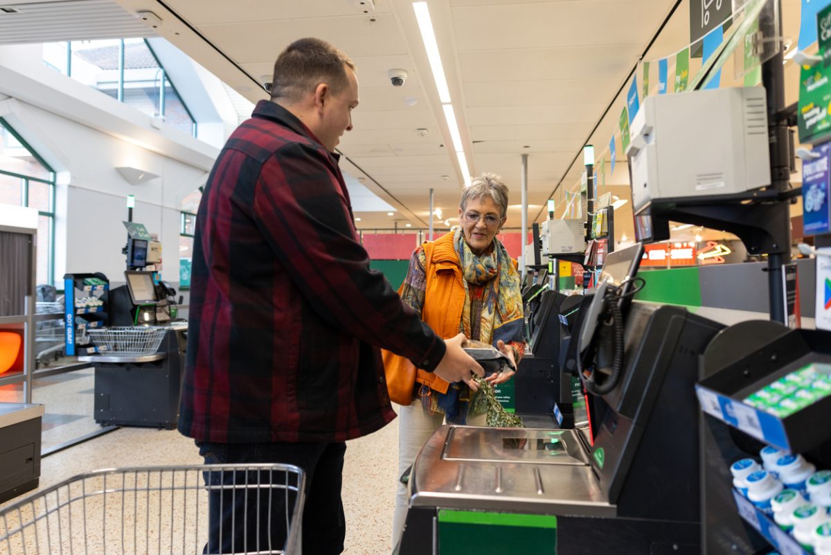 A man and a woman at a supermarket self-serve checkout