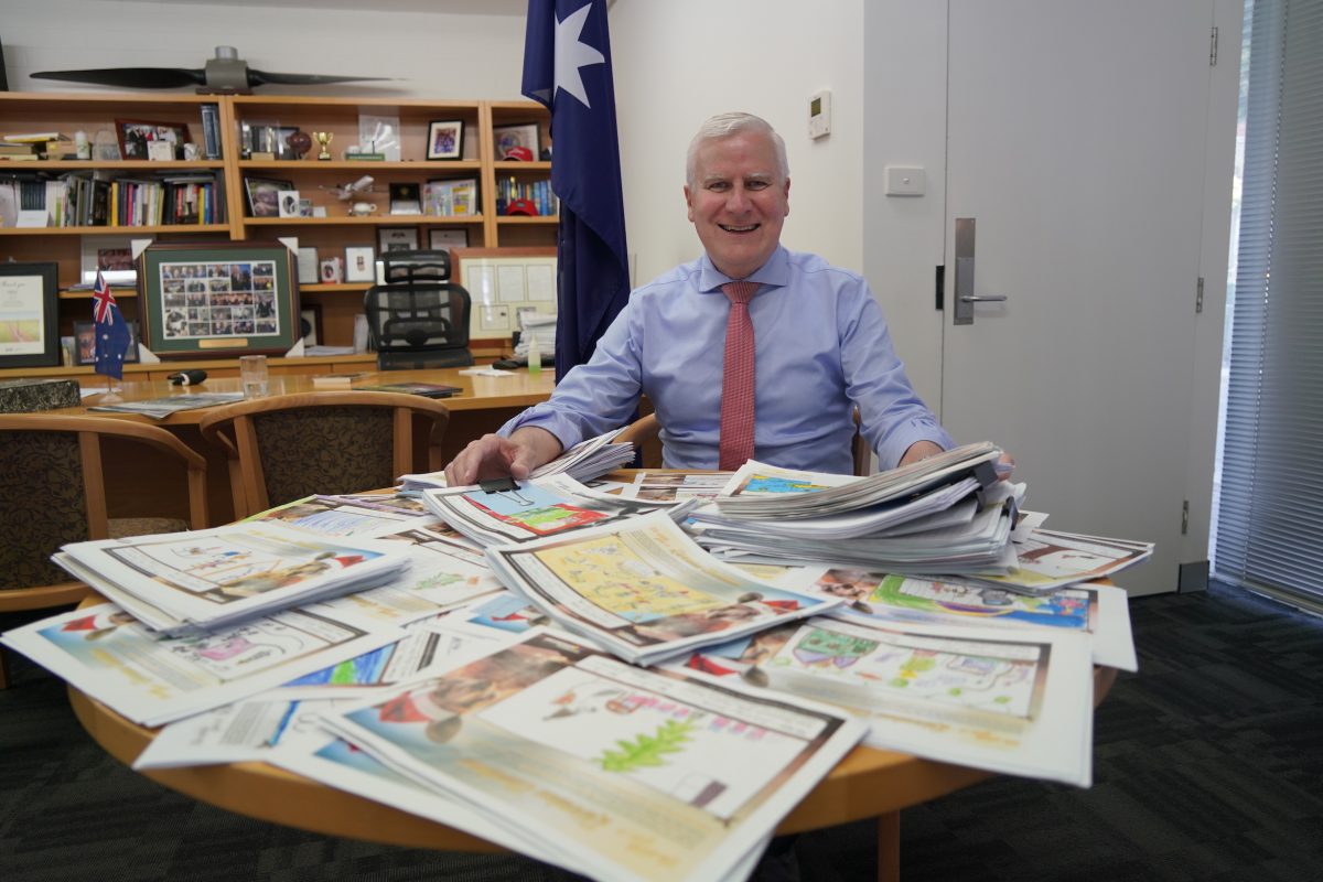 A man at his office desk with Christmas cards designed by school students as part of a competition