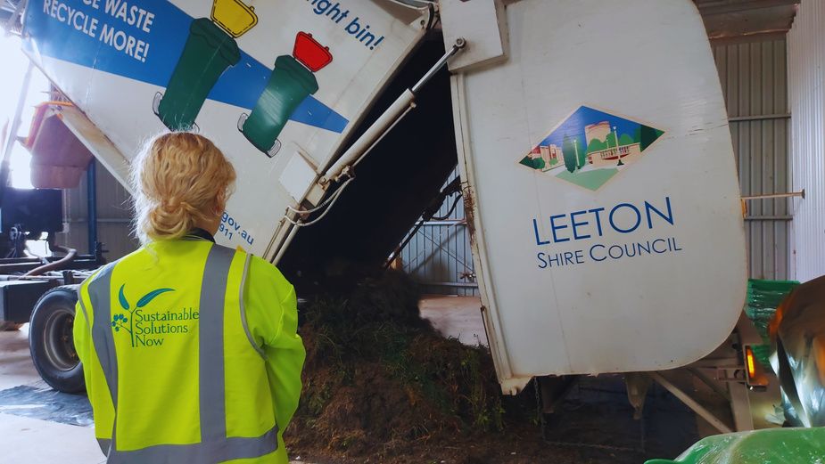 a council worker watching a truck dump organic waste for recycling