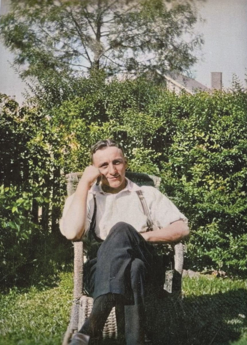 The picture is displayed in the Museum of the Riverina. The full picture of the man sitting on a cane chair wearing braces and clothing that suggests the 1930s or 1940s.