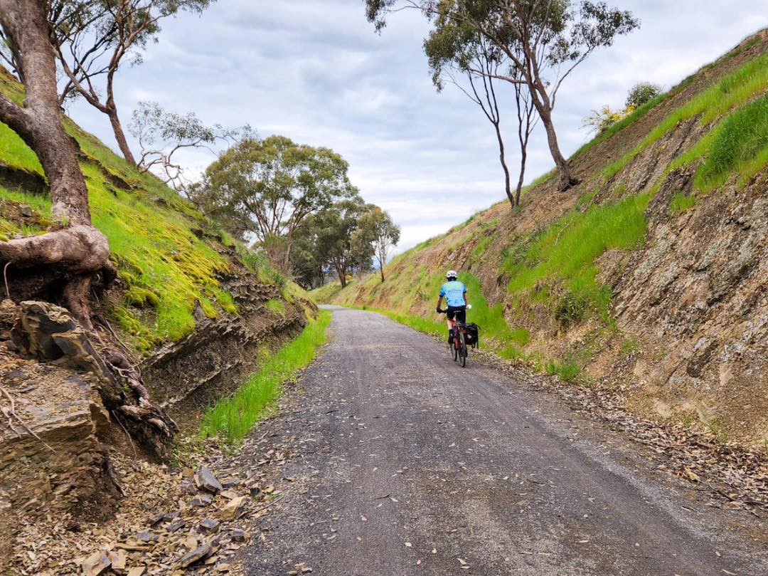 a cyclist riding uphill on a rail trail