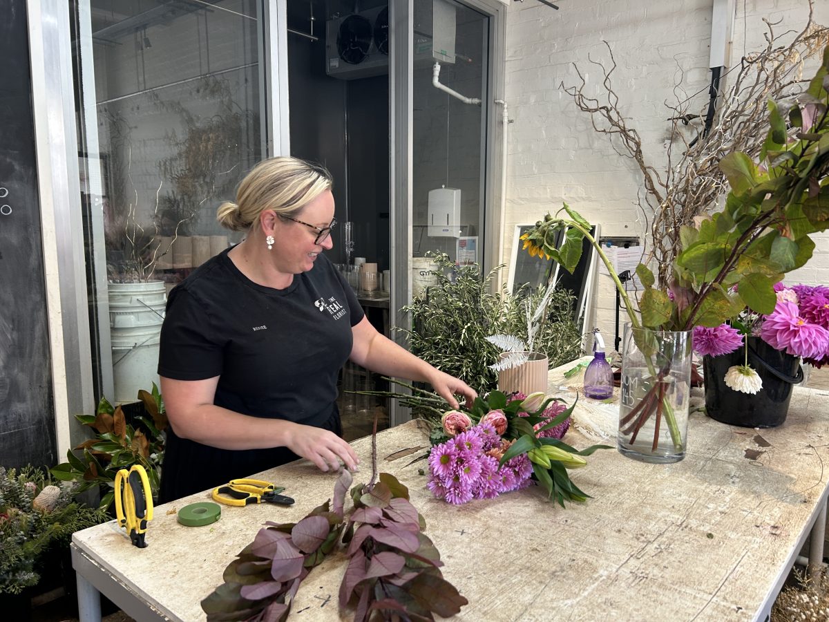 Female florist gathers flowers at her workbench
