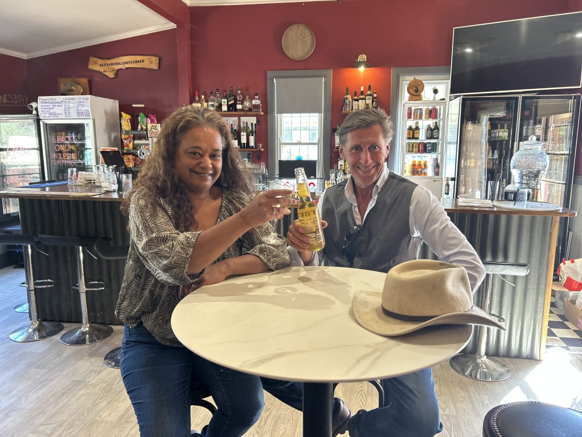 Man and lady clink glasses in front of bar