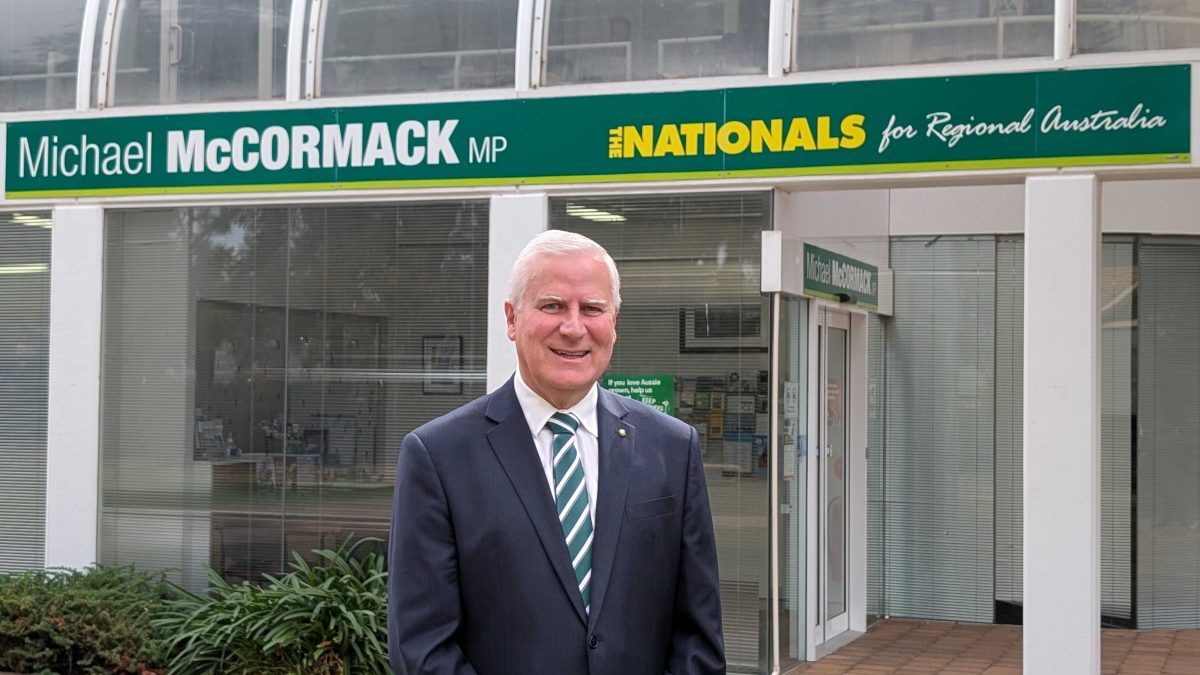 smiling man in a suit standing outside his office