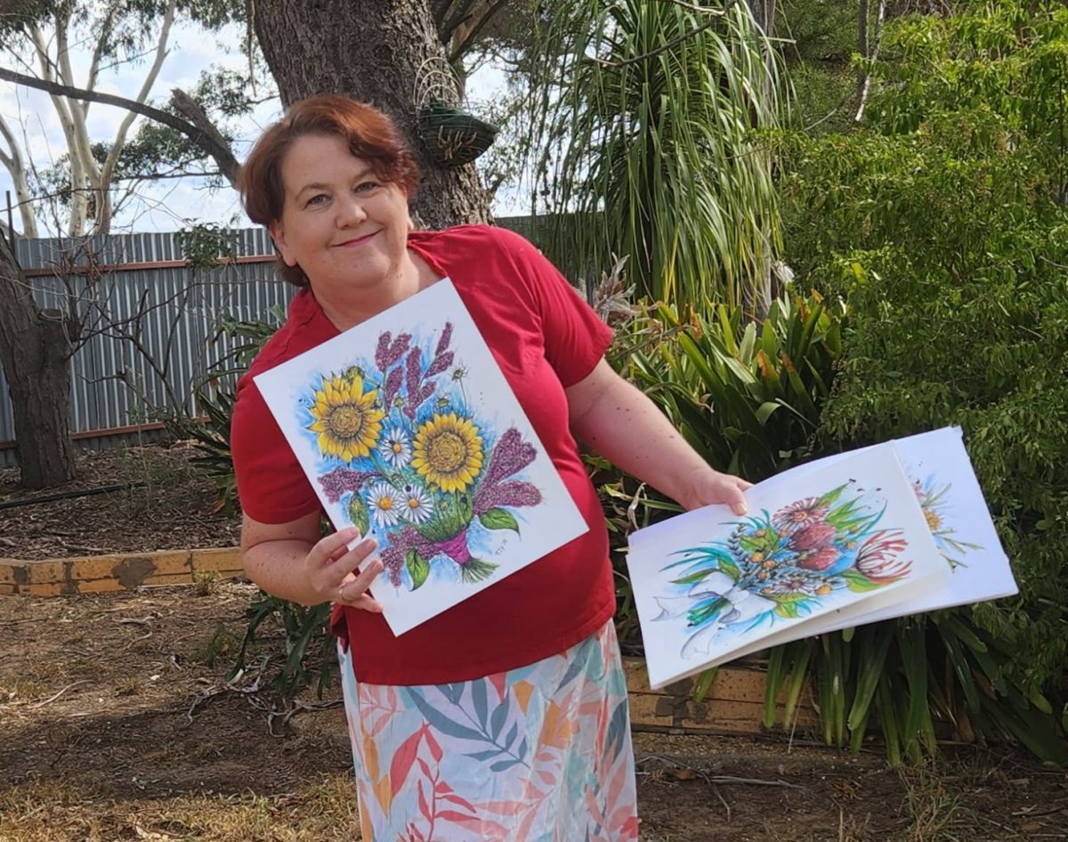 Woman holding up her art pieces.