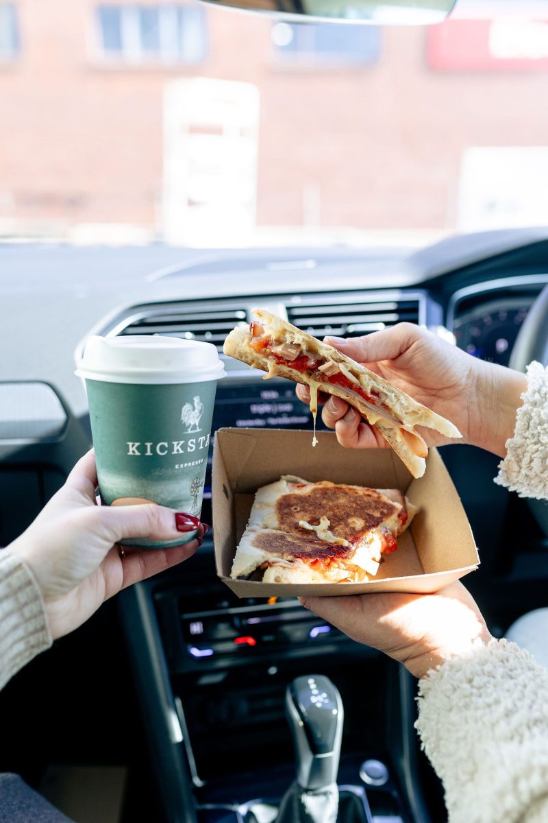 People with a toastie and a coffee in a car