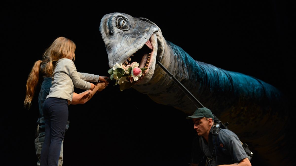 a man and kids with a model of a dinosaur