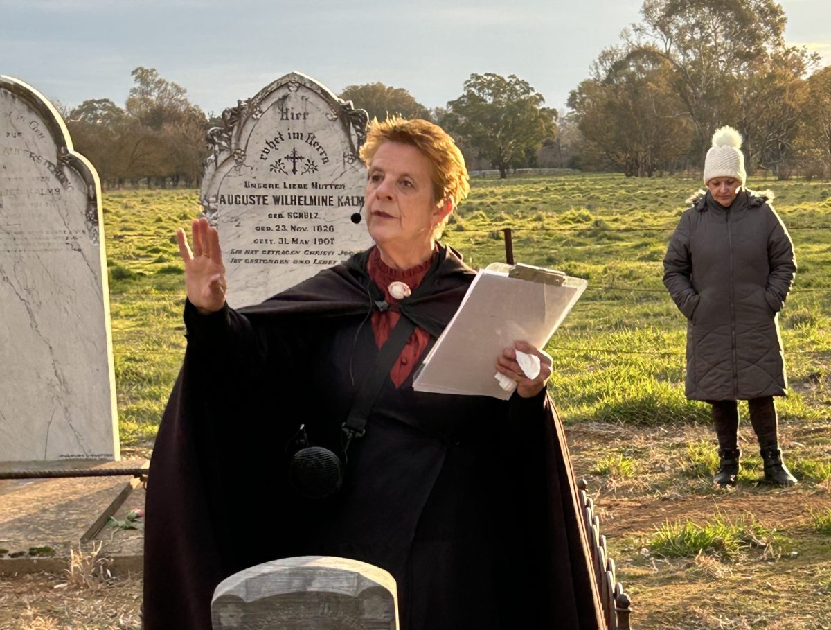 Tour guide stands in front of headstone