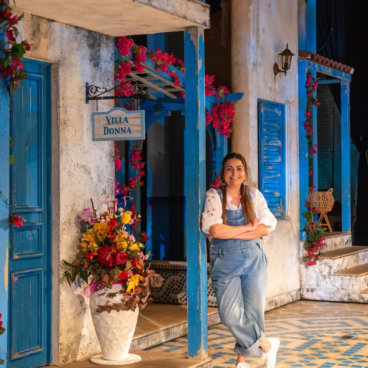 woman on a theatre stage decorated like a Greek island
