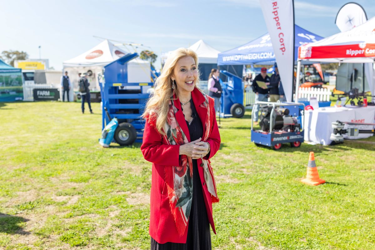 Woman in red coat addressing a crowd at an outdoor event