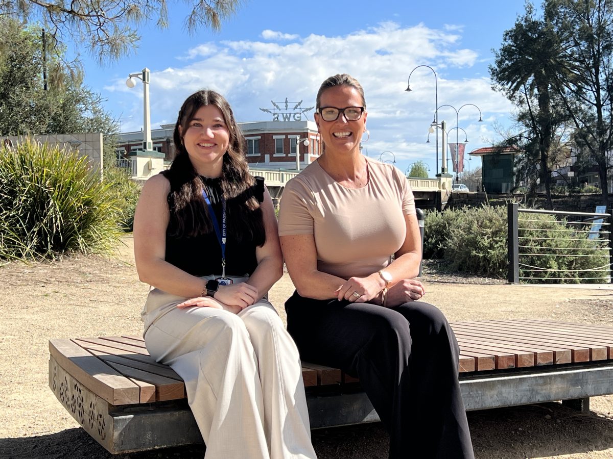 two smiling women sitting on a park bench