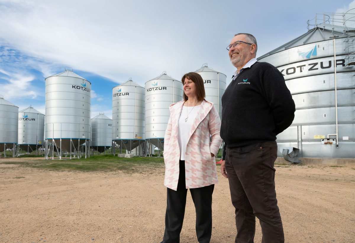 Man and woman in front of grain silos