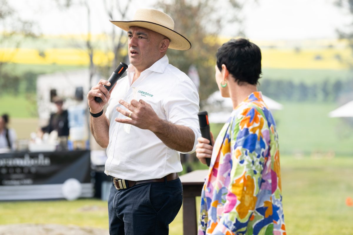 a man and a woman holding microphones to address a crowd at an outdoor meeting
