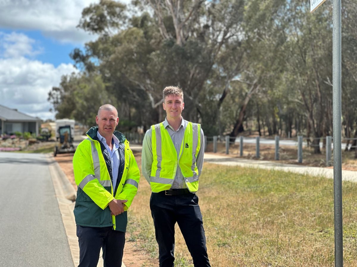 two men standing on a footpath and wearing hi-vis vests
