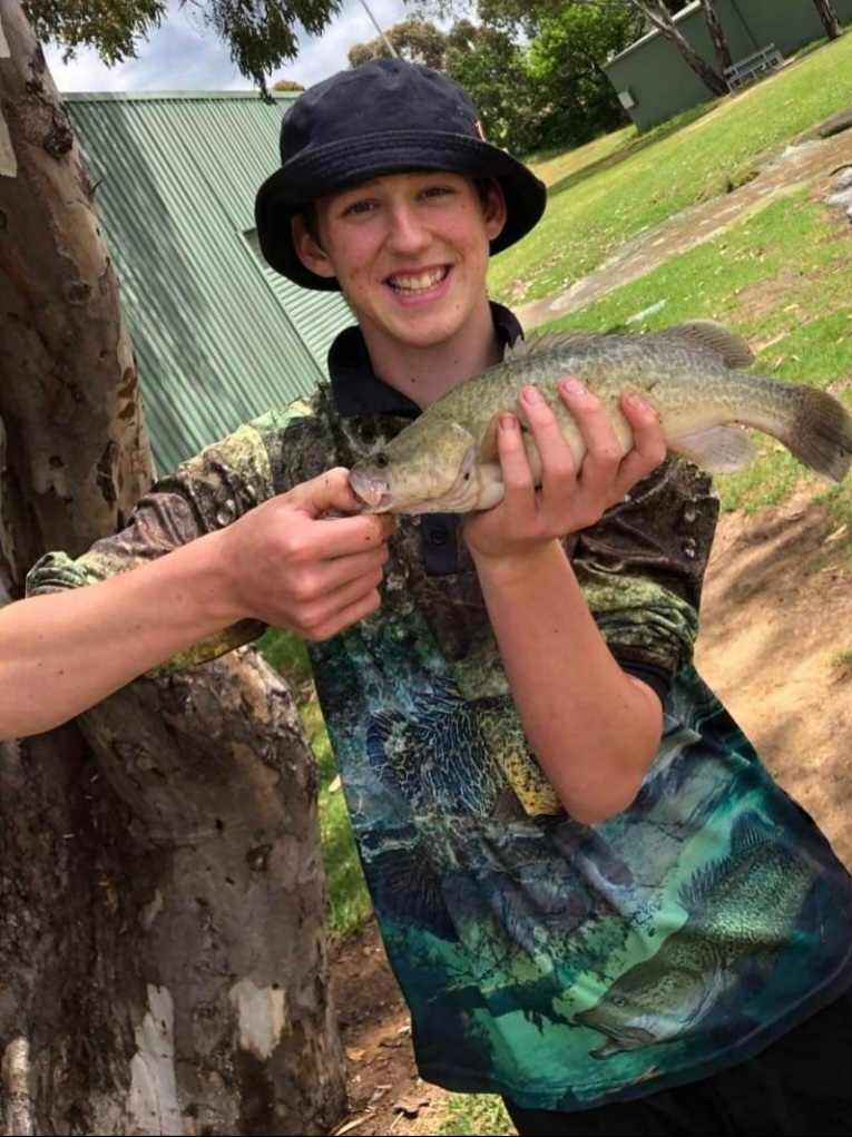 teenage boy holding a fish