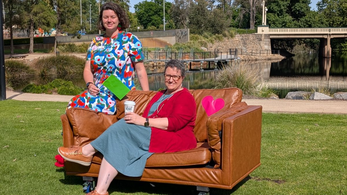 two women sitting outside on a couch