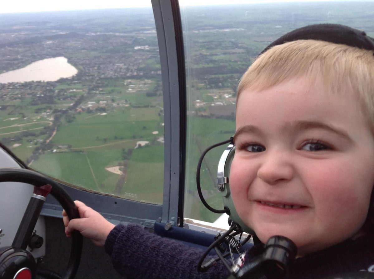 A toddler in the cockpit of a small plane above a town