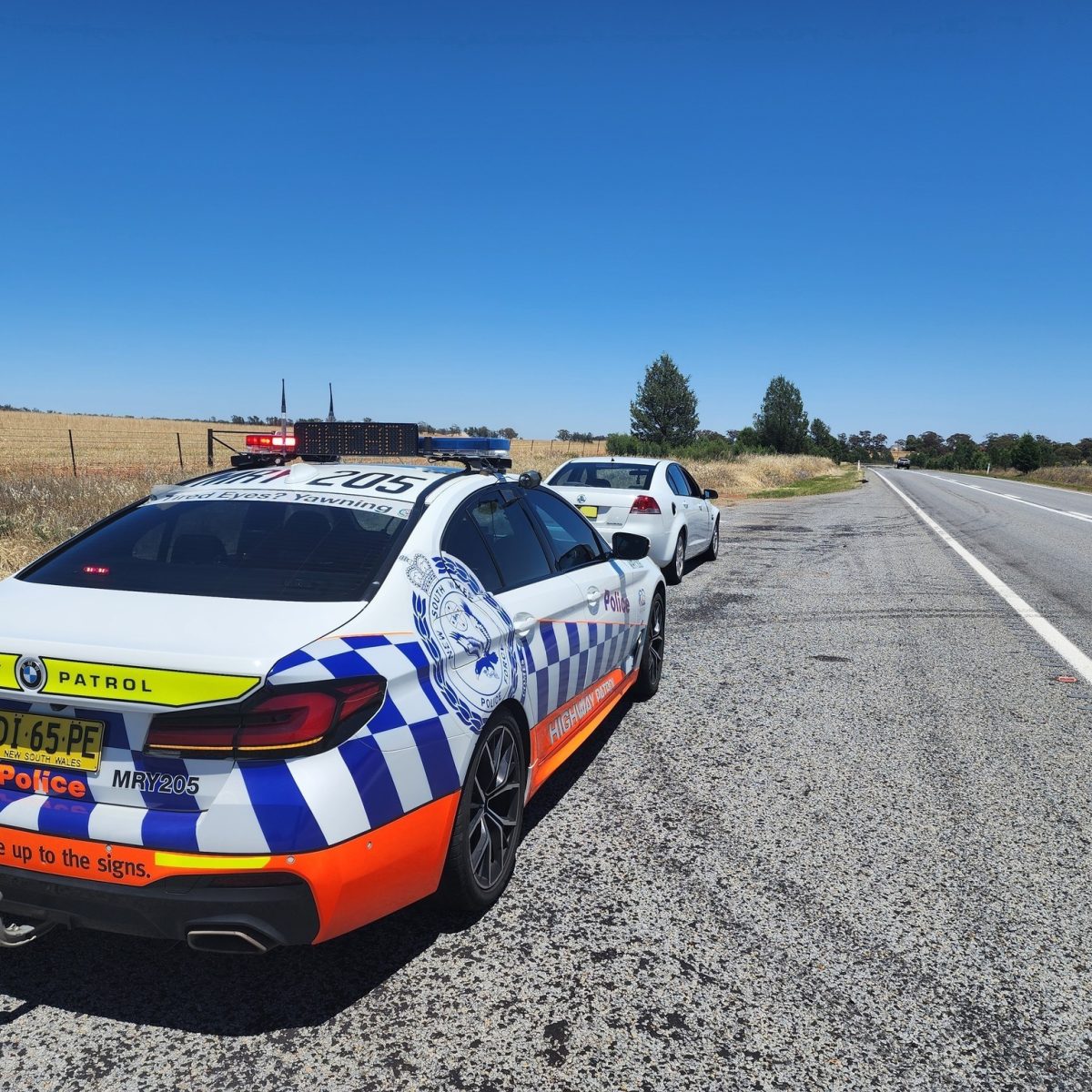 Police car and Commodore on the side of the road. 