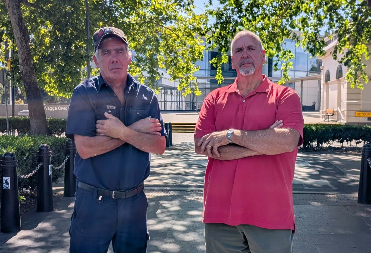 two men standing with their arms folded