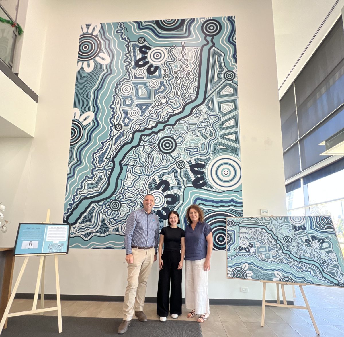 Three people with Indigenous art