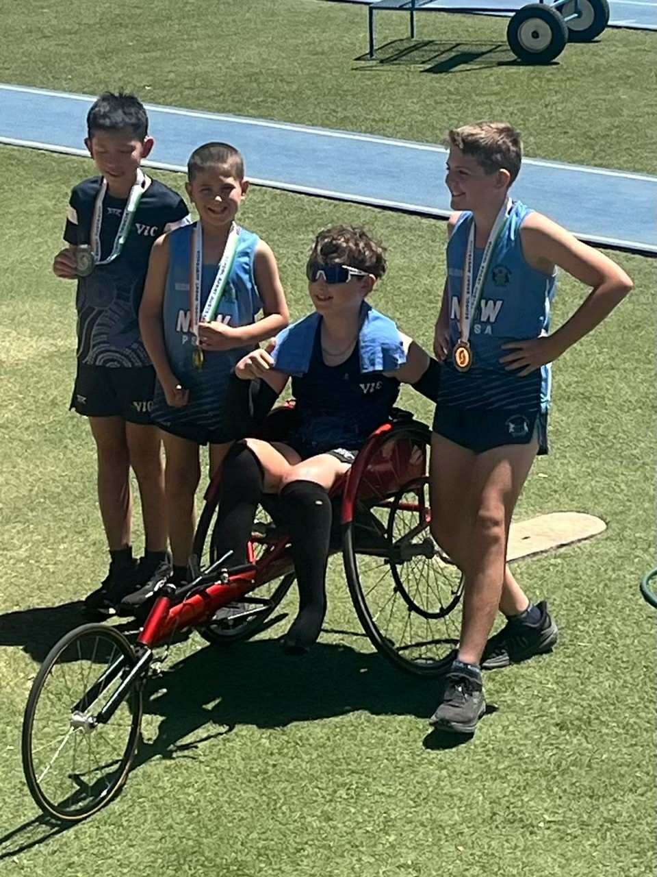 Cody Wheeler at the podium with his three teammates after winning gold in the 4 x 100 combined relay featuring.