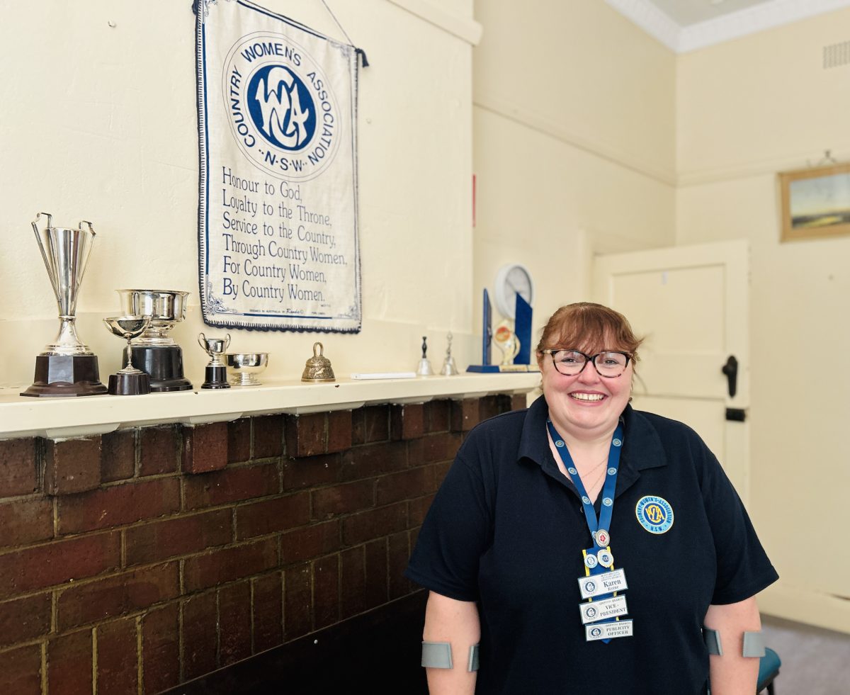 woman in front of sign and trophies